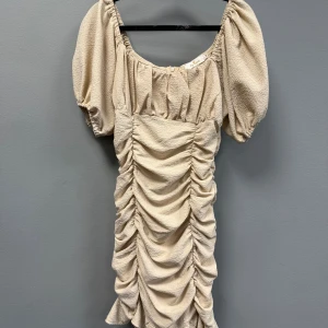 Beige kort omlottklänning med puffärm - Supersöt beige kortklänning med puffärmar och snygg rynkad effekt framtill, passar S och M💗