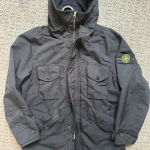 Vintage parkajacka från Stone Island - Svart parkajacka från Stone Island med ikonisk patch på ärmen. Jackan har huva, flera stora fickor med knappar och dragkedja framtill. Tillverkad i slitstark polyester, perfekt för kalla dagar. Snygg och funktionell design med normal passform. Jacka i storlek S, alla lappar är bortklippta både uppe och nere, patchan följer inte med. OBS: Skickas ej! Bara avhämtning eller inbyte mot något annat Stone Island i Göteborgsområdet. Mvh.
