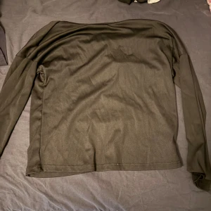 Svart långärmad topp med spetsdetalj - Svart långärmad topp med snygg spetsdetalj i form av en fjäril på ryggen. Tunt och mjukt material som känns skönt mot huden. Perfekt för dig som vill ha något enkelt men ändå med en cool twist i ryggen.