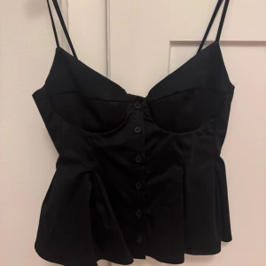 Svart korsett-topp från Zara - Supersnygg svart korsett-topp från Zara med smala axelband och knappar framtill. (Använd 1 gång)