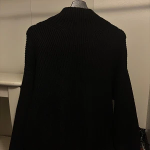 Svart stickad tröja med polokrage - En svart, grovstickad tröja med polokrage och långa ärmar. Har en liten slit i armen. Har tyvär inte fler bilder då den är nedpackad. 