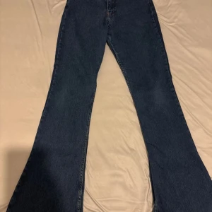 Mörkblå bootcut jeans - Säljer ett par mörkblå jeans med bootcut-modell och klassisk femficksdesign. Jeansen har en snygg utsvängd passform nertill och är tillverkade i ett robust denimtyg. Perfekta för dig som gillar retrovibbar och vill sticka ut lite extra.