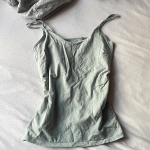 Ljusgrön linnetopp från 157 - Nu Snygg ljusgrön linnetopp från 157 med smala axelband och v-ringad hals. Toppen är tillverkad i mjuk bomull med lite stretch för skön passform. Perfekt att styla med jeans eller shorts för en chill look.