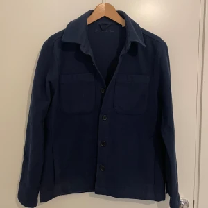 Mörkblå overshirt från Donce De la Sense - Snygg mörkblå overshirt från Donce De la Sense i storlek XS. Jackan har två stora bröstfickor, klassisk krage och knäppning med svarta knappar framtill. Materialet är mjukt och känns som ull, perfekt nu under höst och vinter. Använd fåtal gånger och 9/10 skick. Inga defekter. Nypris 1500 mitt pris 750.