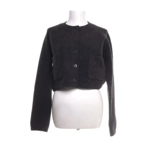 Mörkgrå croppad kofta från Zara - Mysig mörkgrå croppad kofta från Zara med stora knappar framtill och två fickor. Koftan har lång ärm och är stickad i ett mjukt material som passar perfekt till höst och vinter. Enkel och stilren design som är lätt att matcha.