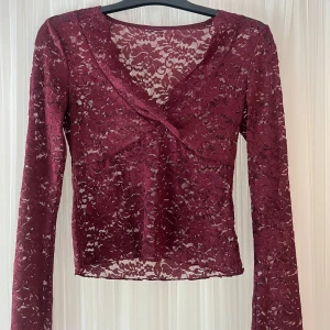 Vinröd spetsblus med v-ringning - Säljer en vinröd långärmad blus i genombruten spets med v-ringning och figurnära passform. Blusen har fina spetsdetaljer och är perfekt för dig som gillar romantisk stil. Köpte på Vinted men va för stor ❤️