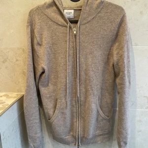 Beige kashmirhoodie från John Henric XS - Mjuk och lyxig beige hoodie i 100% kashmir från John Henric. Tröjan har dragkedja framtill, två fickor och huva med snörning. Perfekt för dig som gillar en clean och chill stil med premiumkänsla.