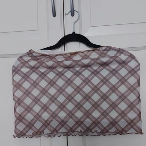 Rutig mesh kjol från H&M Divided - ⚠️ Skriv till mig innan köp!⚠️Säljer en rutig mesh kjol från H&M Divided i beige och brunt. Toppen har en liten rosett framtill, volangkant nertill och är axelbandslös. Materialet är tunn polyester med stretch och toppen är croppad för en trendig look.