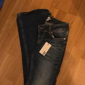 Blå flare jeans Blaze från 157 XS - Snygga blå jeans från 157 i modellen Blaze med super låg midja och utsvängda ben. Jeansen har klassisk femficksdesign, läderpatch bak och är i kortare längd. Perfekta för dig som gillar retrovibbar och vill sticka ut med en flare fit. Säljes då jag köpte 2 par och glömt lämna tillbaka de andra då närmaste butik är 1h bort! Nypris 400!