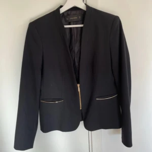 Svart kavaj med gulddetaljer - Svart kavaj med gulddetaljer. Kavajen kommer från Zara och är i strl M. Mycket fint skick!