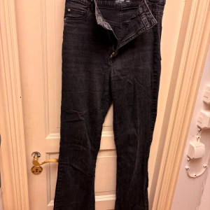 Svarta bootcut jeans Cubus Stl M - Svarta jeans från Cubus med hög midja och bootcut. Jeansen har klassisk femficksdesign, dragkedja och knapp framtill. Materialet är jeans med en mörk tvätt som ger en cool och avslappnad vibe. Storlek M.