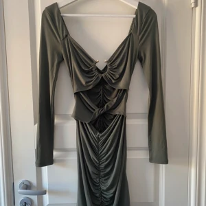 Olivgrön ruched klänning ASOS  - Säljer en fantastisk långärmad olivgrön klänning från ASOS, med söt hjärtformad halsringning och rynkad fram och bakom. Den har en fin cut-out detalj vid magen och guldfärgade ring vid brösten. Använd endast 1 gång och i nyskick! Perfekt för en kväll ute eller fest. 😊  Vänligen läs min bio innan du gör ett köp; där hittar du bland annat information om leveransprocessen med mera 😊   #ASOS #klänning #olivgrön #nyskick #mode #fest