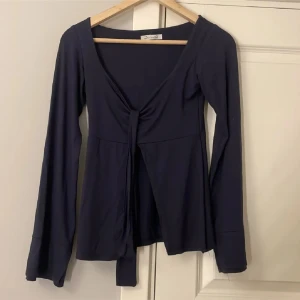  Design by Si topp - Mörkblå topp från Design by Si med knytning framtill. Toppen har långa ärmar och är v-ringad. I storlek xs/s