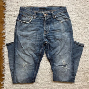 NUDIES MED SLITNINGAR - Säljer nu dessa sjukt unika nudie jeans i en perfekt comorway enligt mig!!🎨| Slitningarna är mycket snyggt gjorda och fantastiskt snygga!!🪡| Båda framfickorna har flera lagningar men fyller fortfarande sina syften!! | Modellen kallas ”Steady Eddie” och är perfekt till hösten då den sitter mer rakt!!🌤️🍁| Storlek 29/32 på lappen men passar 31/32! | Hör gärna av dig!!✌🏻👑