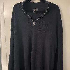 Mörkblå stickad tröja med half zip - Mysig mörkblå stickad tröja med hög krage och snygg half zip-dragkedja framtill. Perfekt för lager-på-lager och chill dagar. Långärmad och i klassisk modell som funkar till det mesta. Står L på tröjan men passar XL