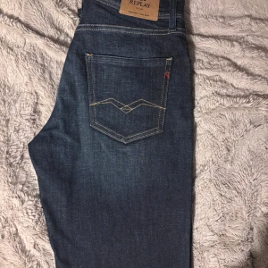 Replay mörkblå jeans med raka ben - Snygga mörkblå jeans från Replay med klassisk femficksdesign och kontrastsömmar. Modellen har raka ben och normal passform, med Replay-logga på fickan och bak på linningen. Perfekt för dig som gillar stilrena och tidlösa jeans.