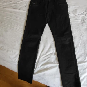 Svarta Diesel D-Bazer jeans tapered - Svarta jeans från Diesel, modell D-Bazer med tapered passform. Klassisk femficksdesign, smalare ben och normal midja. Snygga och stilrena byxor i jeansmaterial, perfekta till en streetwear-look. Mycket fint skick W29 L30