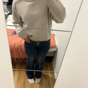 Blå unika jeans från Bershka - Säljer ett par blå jeans från Bershka i storlek 34. De har låg midja, bootcut-ben och tre snygga knappar framtill🥰 nyskick!