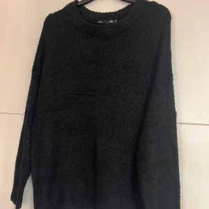 Svart stickad tröja  - En svart stickad tröja från med rund halsringning och långa ärmar. Tröjan har en loose passform och breda ribbade muddar vid ärmslut och nederkant.