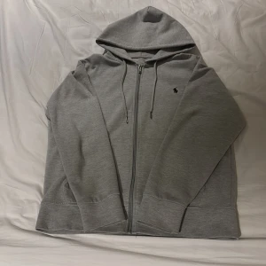 Grå hoodie från Polo Ralph Lauren - Tja, jag säljer min gråa Ralph Lauren tröja för att den nu blivit för liten. Tröjan är bra för att behålla värme alltså perfekt nu inför vinter. Tröjan är använd kanske 5 gånger så den har väldigt bra skick, om det är funderingar eller något jag kan hjälpa till med är det bara att skriva.