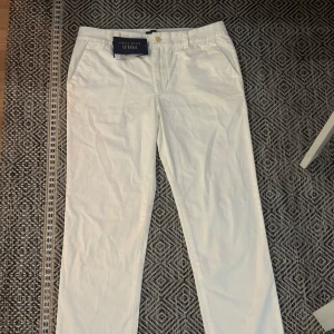 White chinos Polo Ralph Lauren - Snygga vita chinos från Polo Ralph Lauren i 100% bomull. Klassisk rak passform med sidfickor, bakfickor och broderad logga ovanför ena bakfickan. Perfekta för en clean och stilren look. Brand new!