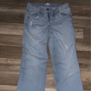 Ljusblå jeans från Gina Tricot - Snygga ljusblå jeans från Gina Tricot i storlek 152. Jeansen har klassisk femficksdesign, slitna detaljer och raka ben. Tillverkade i mjukt denimtyg med knapp och dragkedja framtill. Perfekta för en chill och trendig look.