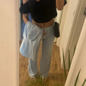 Ljusblå mjukisbyxor med rak passform - Säljer ett par ljusblå mjukisbyxor med rak och loose passform. Byxorna har midwaist och är tillverkade i mjukt bomullsmaterial, perfekta för chill dagar. Byxorna är i acceptabelt skick medans tröjan är i mycket bra skick. De har fläckar jag inte provat behandla därav pris. 
