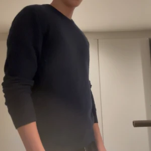 Mörkblå kashmirtröja John Henric - Mysig mörkblå rundhalsad tröja från John Henric i 100% kashmir. Klassisk modell med lång ärm och ribbade muddar. Perfekt för dig som gillar stilrena och sköna plagg med lyxig känsla. Kashmir tröjan passar M/L.