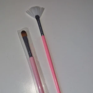 Nagelborstar - Två helt nya nagelborstar med ljusrosa skaft och silverfärgad metall. 