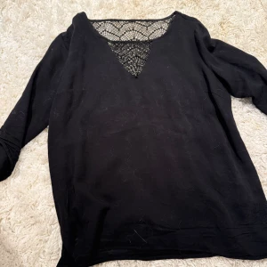 Svart långärmad topp med spets - Svart långärmad topp med snygg v-ringning och dekorativ spetsdetalj upptill. Mjuk och skön, perfekt för dig som gillar en stilren look med lite extra detalj. Passar till både jeans och kjol.