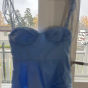 Ljusblå kort Topp/blus  - Supersöt ljusblå tröja med figurnära passform och snörning i ryggen. Tröjan har axelbandslös design och markerad byst med rynkade detaljer. Perfekt för dig som gillar en feminin och trendig look.