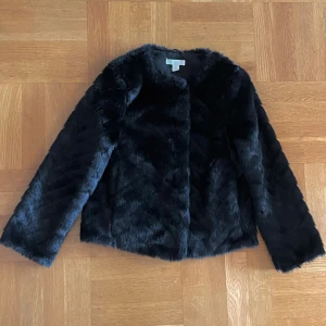 Svart pälsjacka från H&M XS - Snygg svart pälsjacka från H&M i storlek XS, passar även S. Jackan har en mjuk och fluffig yta, raka ärmar och stängs med knappar framtill. Perfekt för dig som vill ha en stilren och trendig look under kyliga dagar 💕