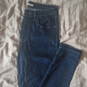 Levi's 511 mörkblå jeans - Säljer ett par klassiska Levi's 511 jeans i mörkblå denim. Modellen har raka ben, fem fickor och tydliga kontrastsömmar. Perfekta för dig som gillar en tidlös och clean look. Färgförändring på vänster knä och i grenen och stretchen är synlig eller hur man ska säga (se bilder). W30 L34