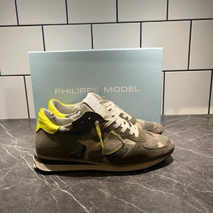 Philippe Model sneakers camouflage - Snygga sneakers från Philippe Model med camouflagemönster i grönt och beige, skorna är i bra skick men dock har bakdelen lossnat lite men går att fixa! Storlek 41 men passar större 
