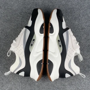 Dior vita och svarta sneakers - Chunky sneakers från Dior i en clean färgkombo av vitt, svart och grått med bruna detaljer på sulan. Ovandelen har mesh och skinnpaneler, perforeringar på sidan och snygga logodetaljer. Platt sula med grovt mönster och dragflik bak för enkel påtagning.