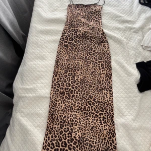 Leopardmönstrad långklänning från Bershka - Säljer en snygg långklänning med leopardmönster och smala axelband. Klänningen har en rak och figurnära passform som ger en cool och trendig look. 