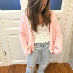 Ljusrosa stickad kofta - Supermjuk och oversized ljusrosa stickad kofta med slouchy passform och långa ärmar. Perfekt att slänga över ett linne eller t-shirt för en chill look. Koftan är öppen framtill och har en riktigt mysig vibe.