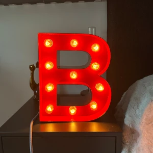 Röd B cirkuslampa  - Unik röd bokstavslampa 'B' från Cirkuslampan, modell Small. Utrustad med flera varma LED-lampor, max 15W, 230V. Perfekt som dekorativ belysning i hemmet. Lampan är i fint skick utan synliga defekter eller slitage. Nypris är 4000 och ljuset är juster bart
