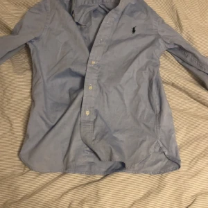 Blå slim fit skjorta från Polo Ralph Lauren - Snygg ljusblå skjorta från Polo Ralph Lauren i slim fit-modell. Passar extremt bra nu pris är 1095kr