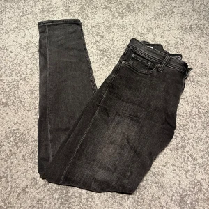 Svarta Slim/Glenn jeans från Jack & Jones - Svarta jeans från Jack & Jones i modellen Slim/Glenn. Snygg slim fit med klassisk femficksdesign och dragkedjegylf. Jeansen är tillverkade i stretchig denim för extra komfort och har en stilren look som passar till det mesta.