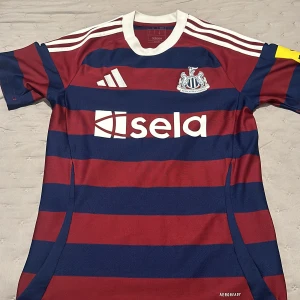 Newcastle United randig fotbollströja S - Säljer en officiell Newcastle United fotbollströja från Adidas i storlek S. Tröjan har breda marinblå och vinröda ränder, vit krage och axelband samt klubbmärke på bröstet. Tillverkad i lätt och ventilerande polyester med AEROREADY-teknologi.