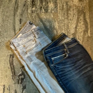 Två par slim fit jeans i blått och ljusgrått - Säljer två par slim fit jeans från jack n jones och lee, ett i mörkblå tvätt med snygga slitningar och ett i ljusgrått. Båda har klassisk femficksdesign och smal passform. Perfekta för dig som gillar en tajt look och vill ha jeans i olika färger att variera mellan.