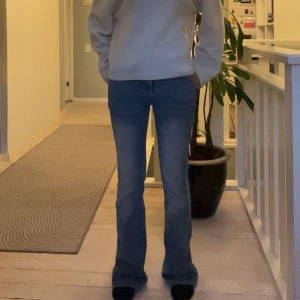 Blå bootcut jeans med fickdetaljer - Snygga blå jeans med bootcut passform och klassiska fickor bak. Jeansen har en medelhög midja och är tillverkade i ett mjukt denimtyg som sitter skönt. Perfekta för dig som gillar en tidlös look med lite utsvängda ben.