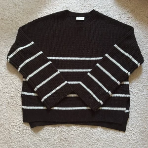 Svartvit randig stickad tröja Kappahl - Säljer en svart stickad tröja från Kappahl med vita horisontella ränder. Tröjan har rund halsringning, långa ärmar och ribbade muddar. Jättefin till ett par byxor eller en kjol