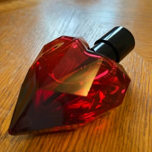 Loverdose red kiss parfym  - Snygg parfymflaska i röd hjärtformad design med svart kork. 30ml.  Toppnot: hasselnöt. Mellannot: apelsinblomma och aprikos. Basnot: vanilj, bärnsten, patchouli, kakao. 
