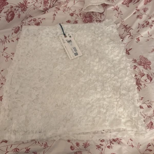 Vit blommig spetskjol från Holly& white  - Nypris 349kr, Superfin vit kortkjol från Holly & white med prislapp på och blommig spets och 3D-blommor över hela tyget. Kjolen har rak passform och Materialet känns lätt och luftigt. Säljer då jag har två