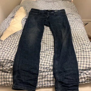 Replay Anbass jeans mörkblå herr - Snygga Replay Anbass jeans i mörkblå tvätt med klassisk femficksdesign och dragkedjegylf. Jeansen är tillverkade i bomull och har raka ben med diskreta slitningar för en cool look. Passar perfekt till en avslappnad streetstil.