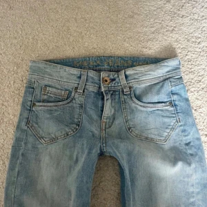 Ljusblå jeans från MEXX - Ljusblå jeans från MEXX med straight fit, klassiska fem fickor och slitna, fransiga benslut. Snygga detaljer på bakfickorna och ett broderat märke bak. Jeansen har en avslappnad vibe och är tillverkade i denim. lågmidjade snygga jeans storlek S:36💗 midjemått 37cm innerbenslängd 75cm fotvidd 18cm pris kan diskuteras vid snabb affär💞