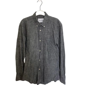 Grå linneskjorta Our Legacy - Snygg grå skjorta från Our Legacy i linne med klassisk krage, bröstficka och vita knappar. Skjortan har lång ärm och en avslappnad passform, perfekt för en stilren look. Nypris cirka 2000.