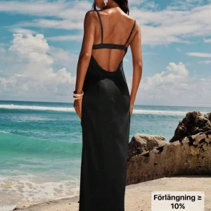 Svart lång klänning - Svart lång klänning med öppen rygg och dragkedja i ryggen. Den är aldrig använd. Men har ingen prislapp kvar. Den är i ett satin liknande material. 